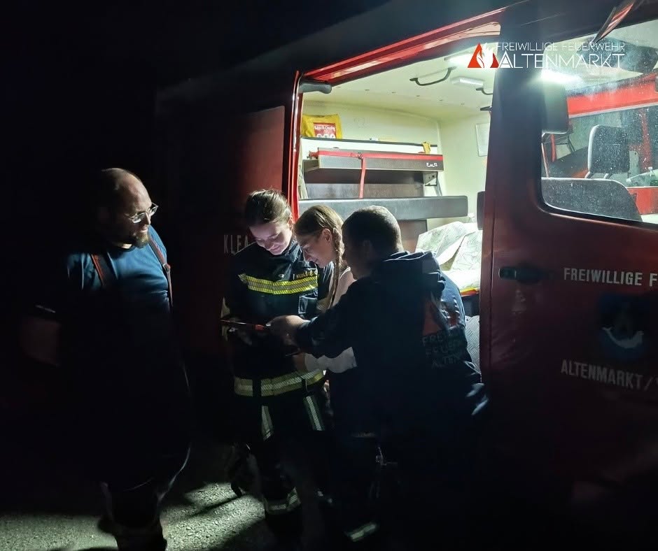 Vier Personen vor einem Feuerwehrauto beim Arbeiten mit einem Tablet.